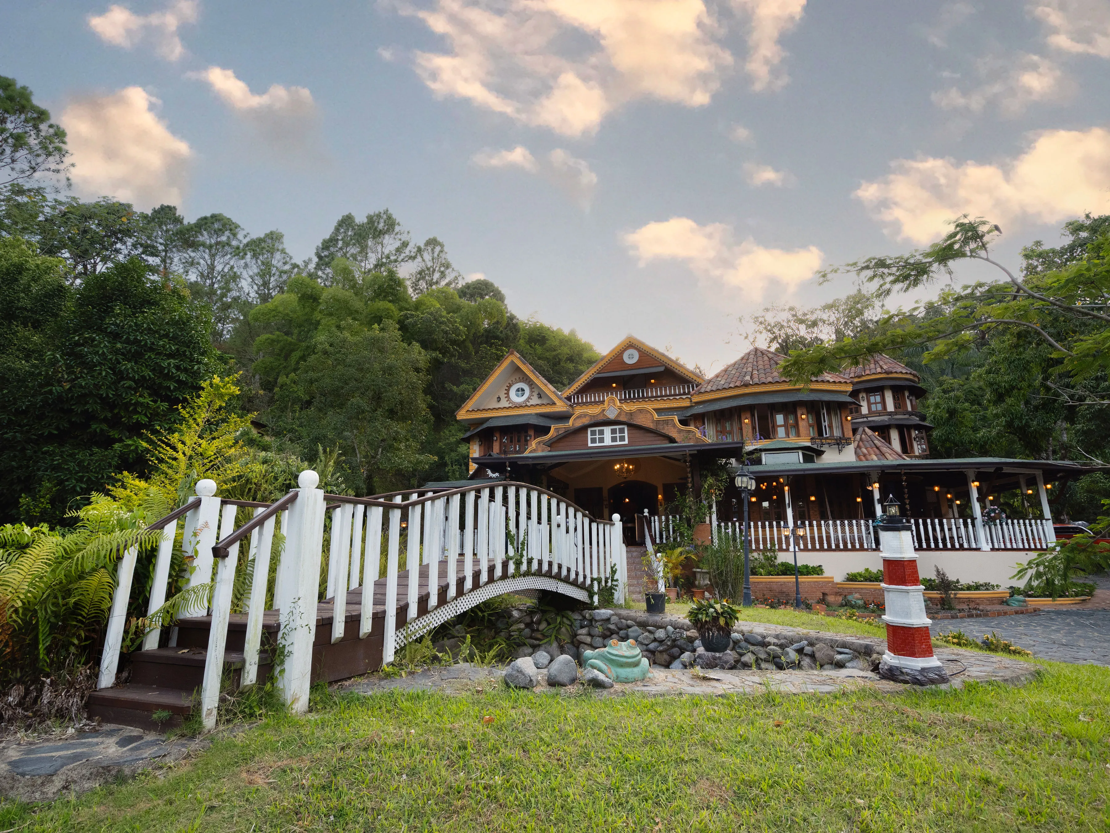 Aerial view of the house and its wraparound porch, tucked into the hillside forest at dusk