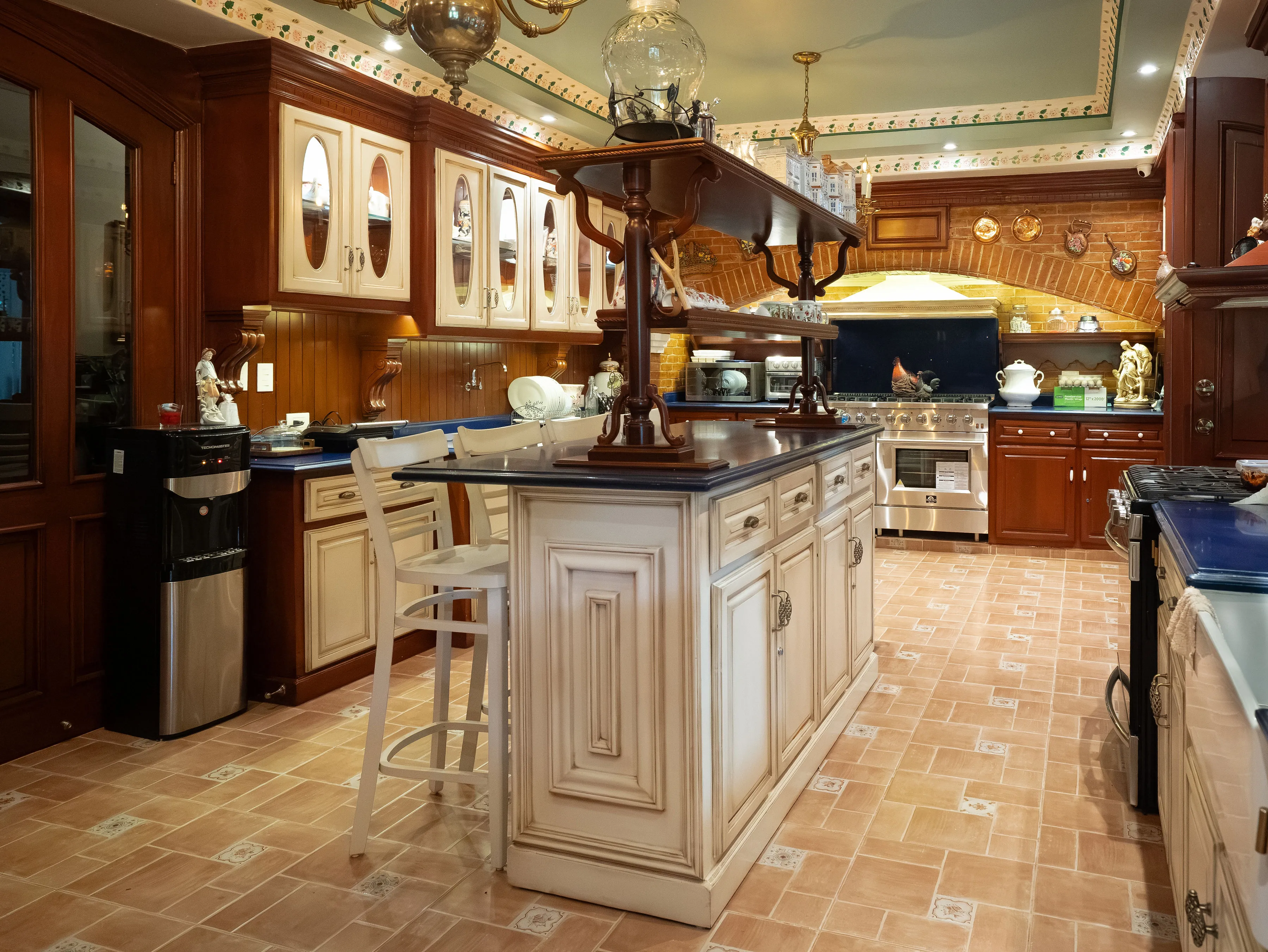 One of the two kitchens, with cream cabinetry and a marble-topped island